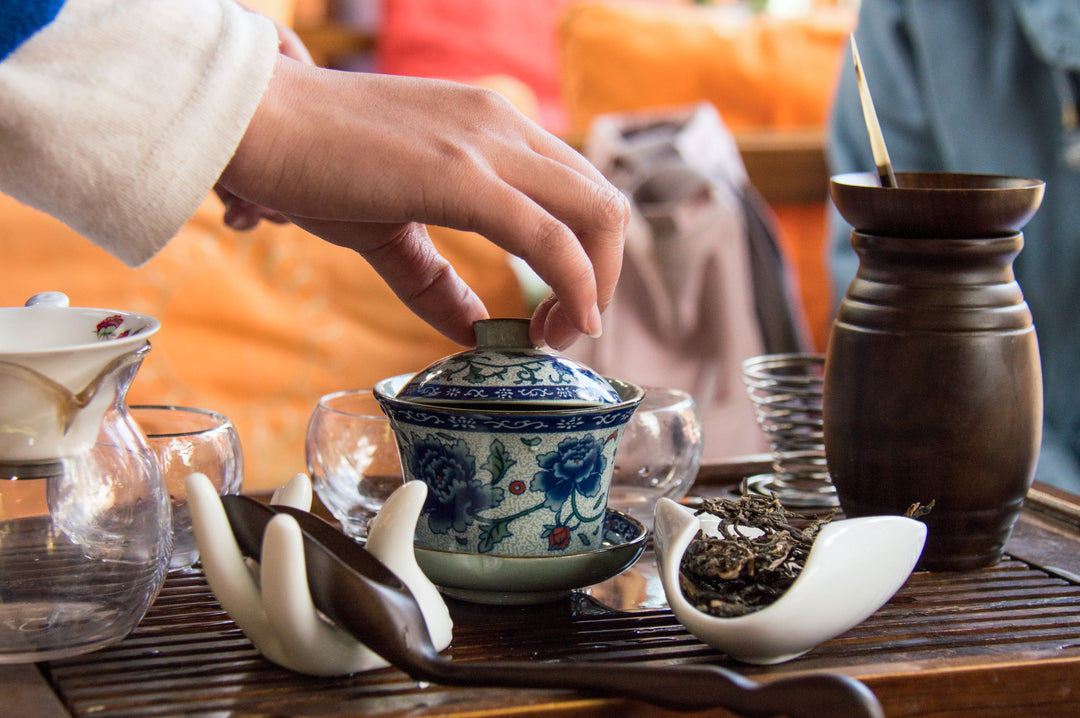 Hand hebt den Deckel von einer Teekanne in Lijiang, Yunnan, China in einem Teehaus.